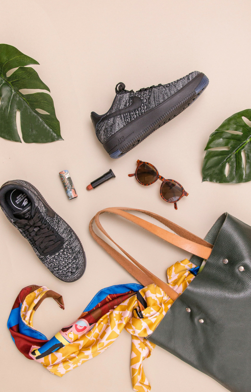 Blog image with one shoe, leaf, sunglasses, and a bag on the nude background