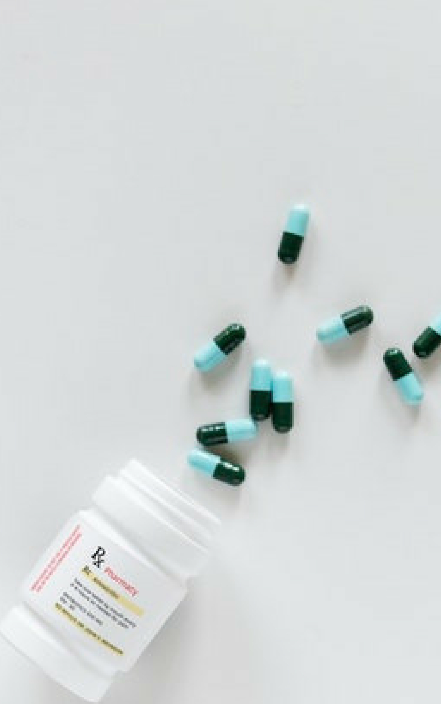 a bottle and green capsules fallen on a white background