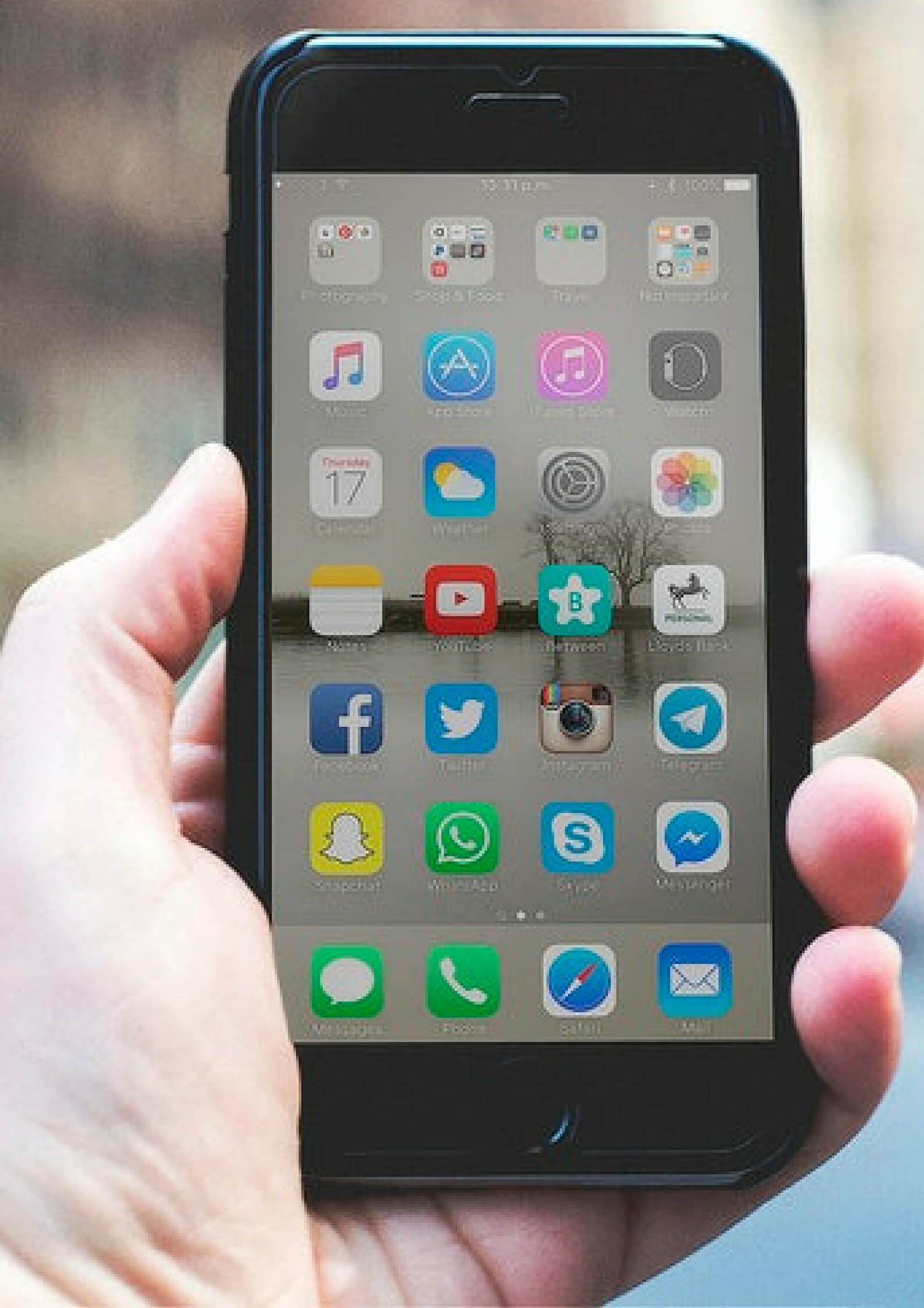 a mobile held on a hand with application icons on the screen