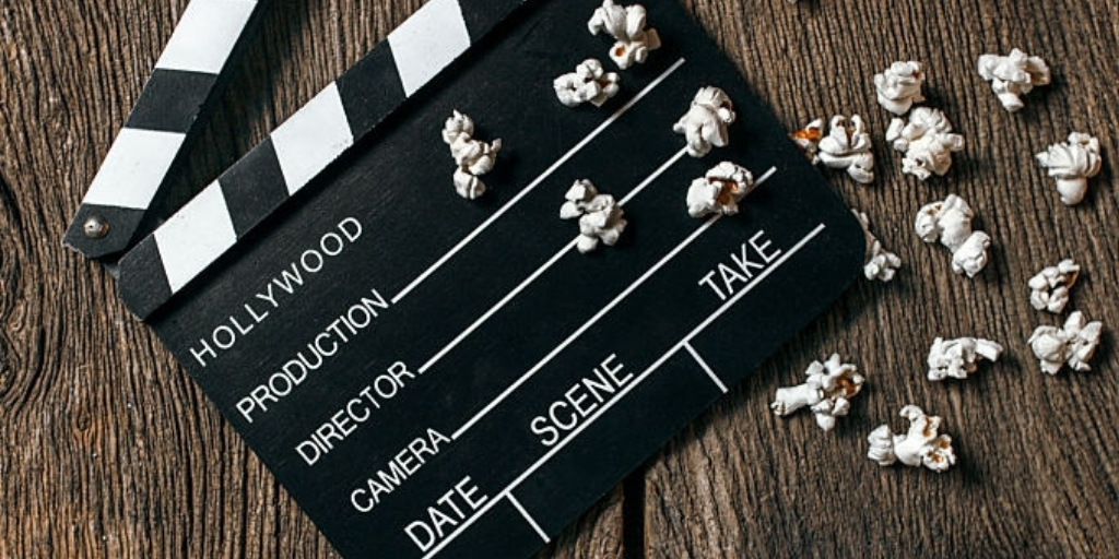 An image of a clapper board placed on a wooden surface with 19 popcorns positioned at the bottom of the clapper board 