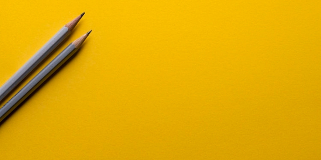 Yellow background with two pencils placed at the left corner 