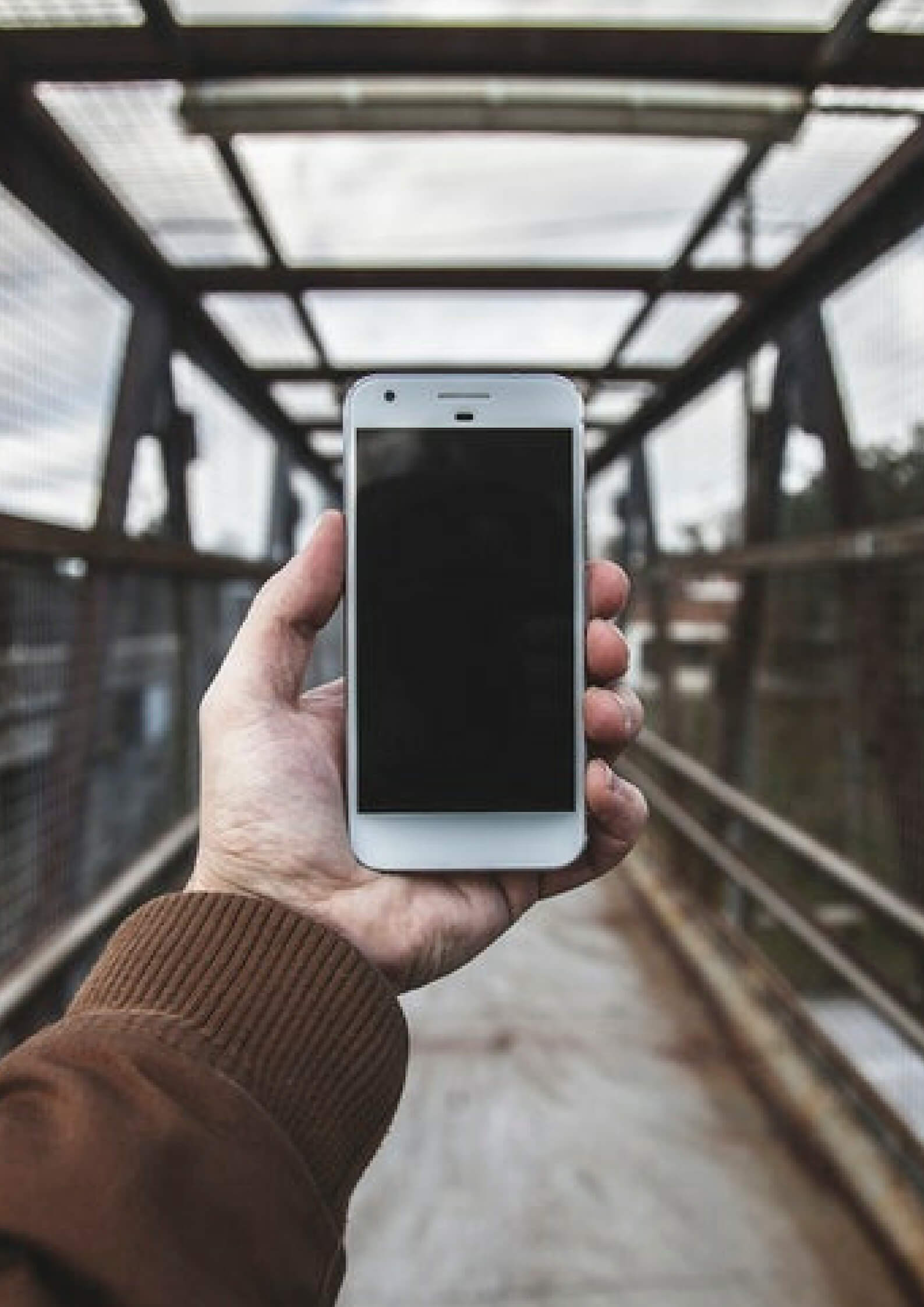 Image of a hand holding a mobile phone with a bridge background 
