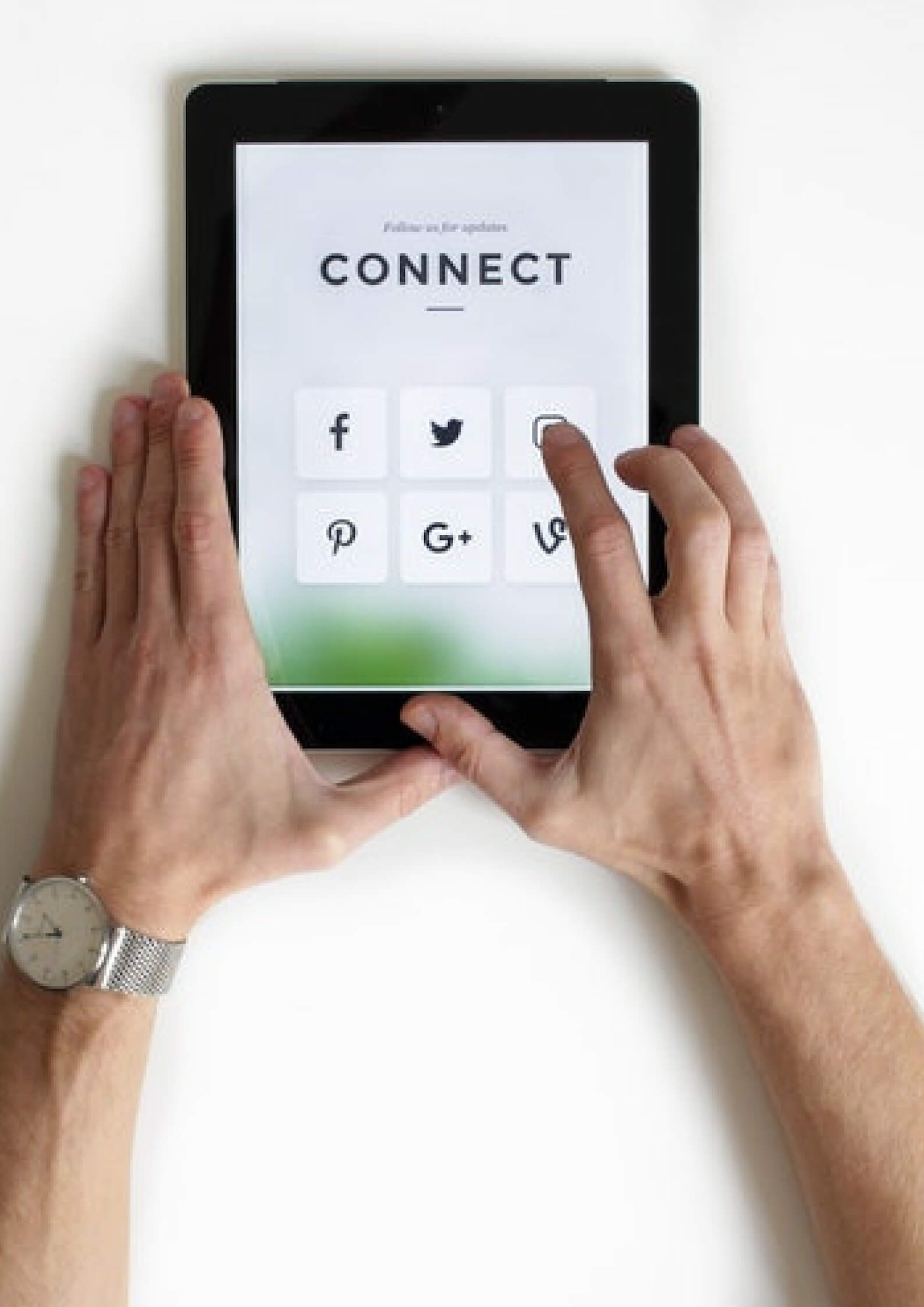 Image of a hands holding a tab in white bacjkground where the screen has social media signs