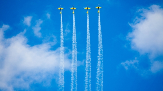 Four jets soaring high above in the sky billowing out white smoke