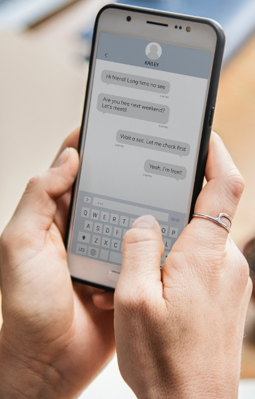 Smartphone being held with two hands with its screen displaying a chat user interface