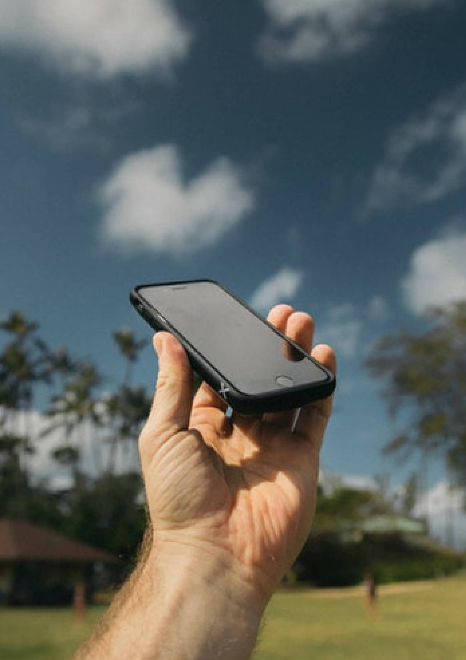 Image of a hand holding a phone in air with clouds as its background 