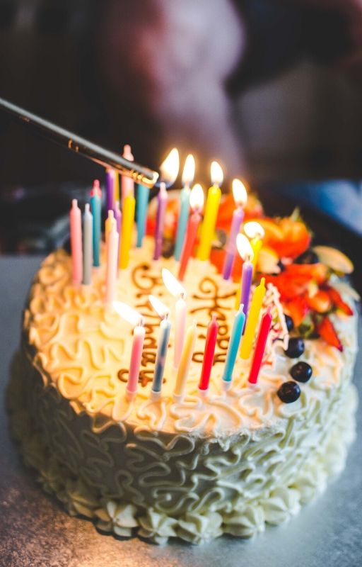 A cake with happy birthday written on top of it and lots of candles fixed over it