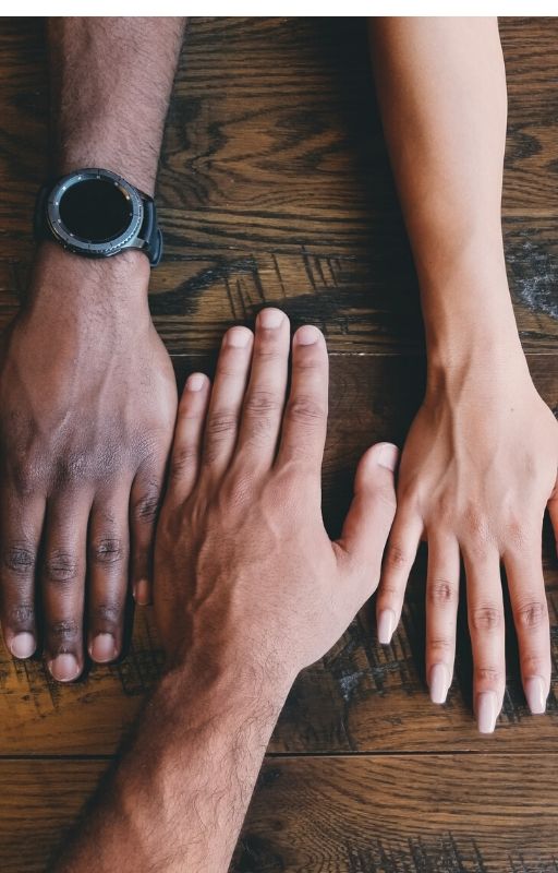 Three hands of different people placed on a table