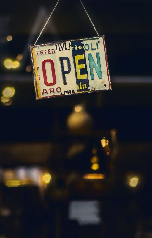 'Open' written on a board hanging outside a shop