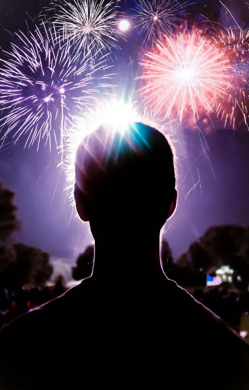 a boy gazing at the night sky full of crackers