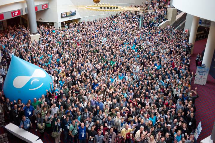 An image of a crowd in an auditorium where the left side is having a big balloon of Drupal logo