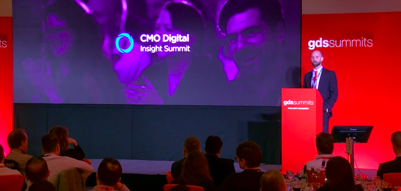 Fabrice Rousseau, Amazon’s general manager of Alexa skills, standing on the stage and several people sitting and listening to him.