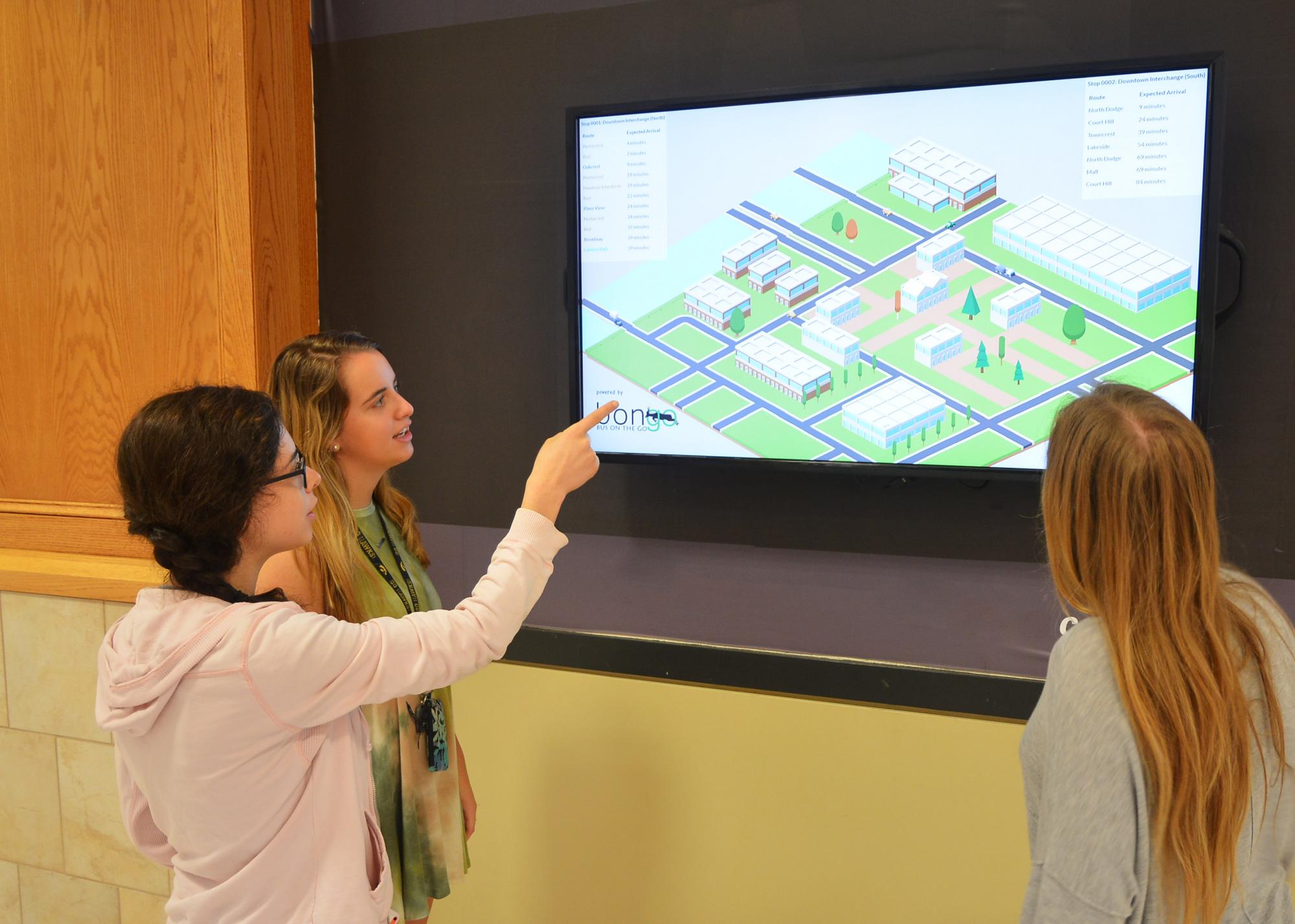 Three girls looking at a screen showing building architecture