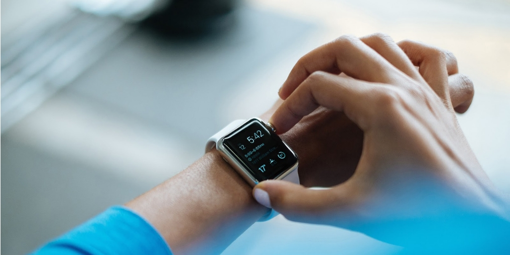 track band on the left wrist and right arm pressing a button on it with a blue foreground on right