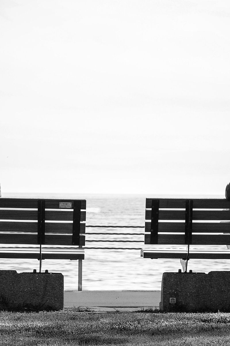 The sides of two benches can be seen on a beach.