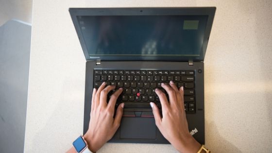 a woman typing on a laptop keyboard
