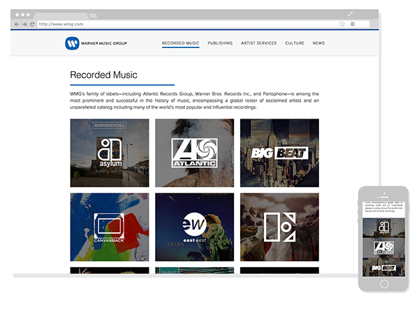 Screenshot of the homepage of Warner Music Group with a mobile phone placed beside it.