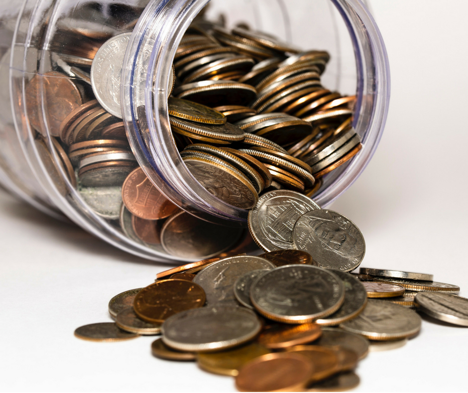 a glass jar open with coins falling from it. 