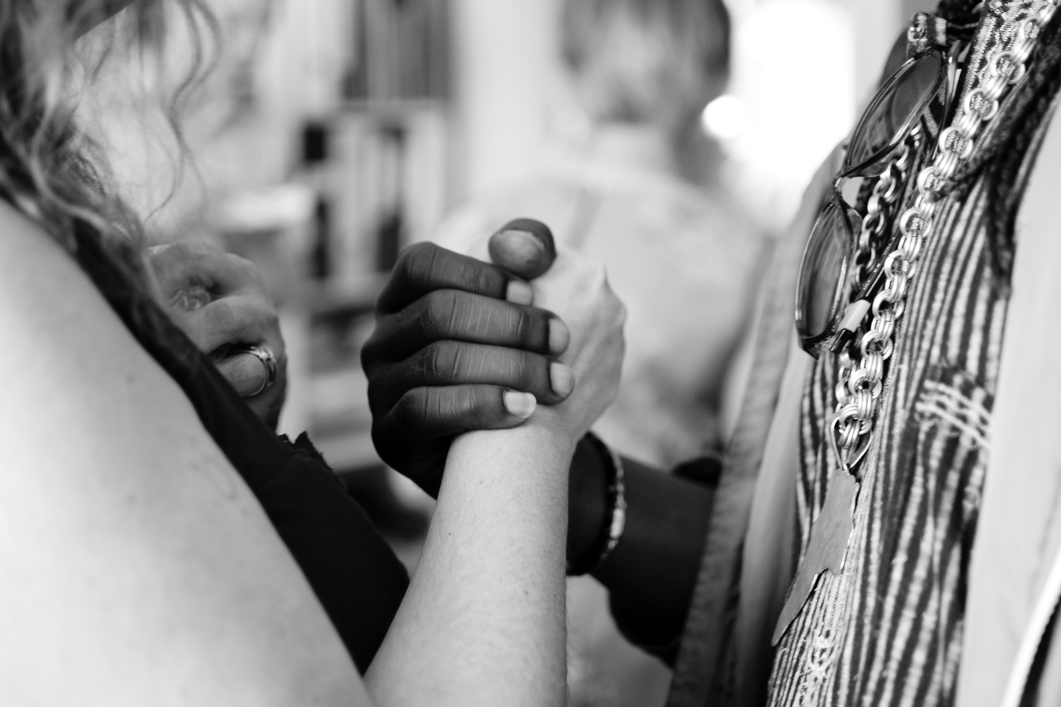 Black and white photography of a white person and a black person holding each others' hands to represent diversity and inclusion