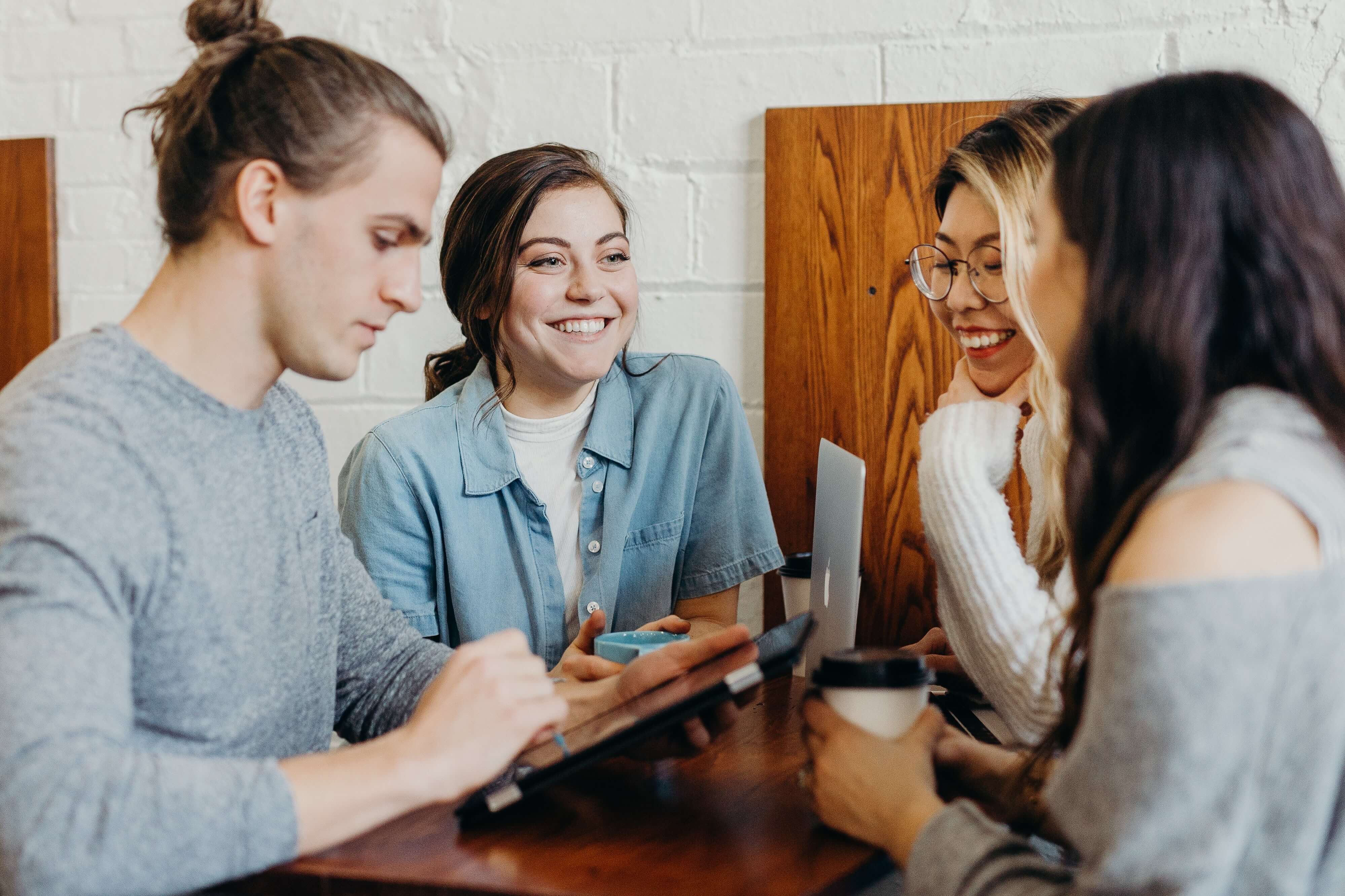 A group of people sitting on a couch and happily talking to each other during one of their team meetings