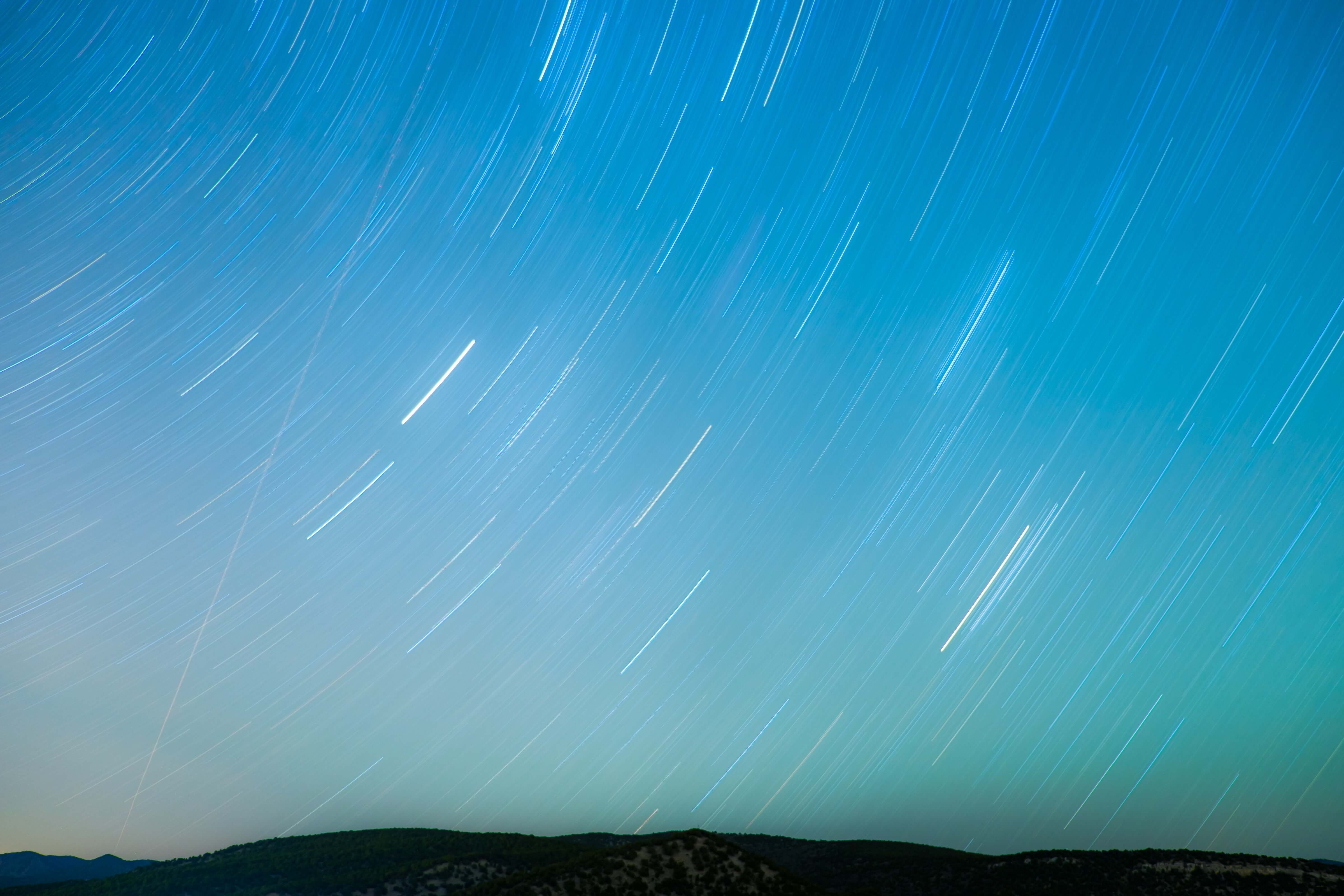 Terraform process of a planet shown through an open sky filled with white curves to resemble shooting stars  