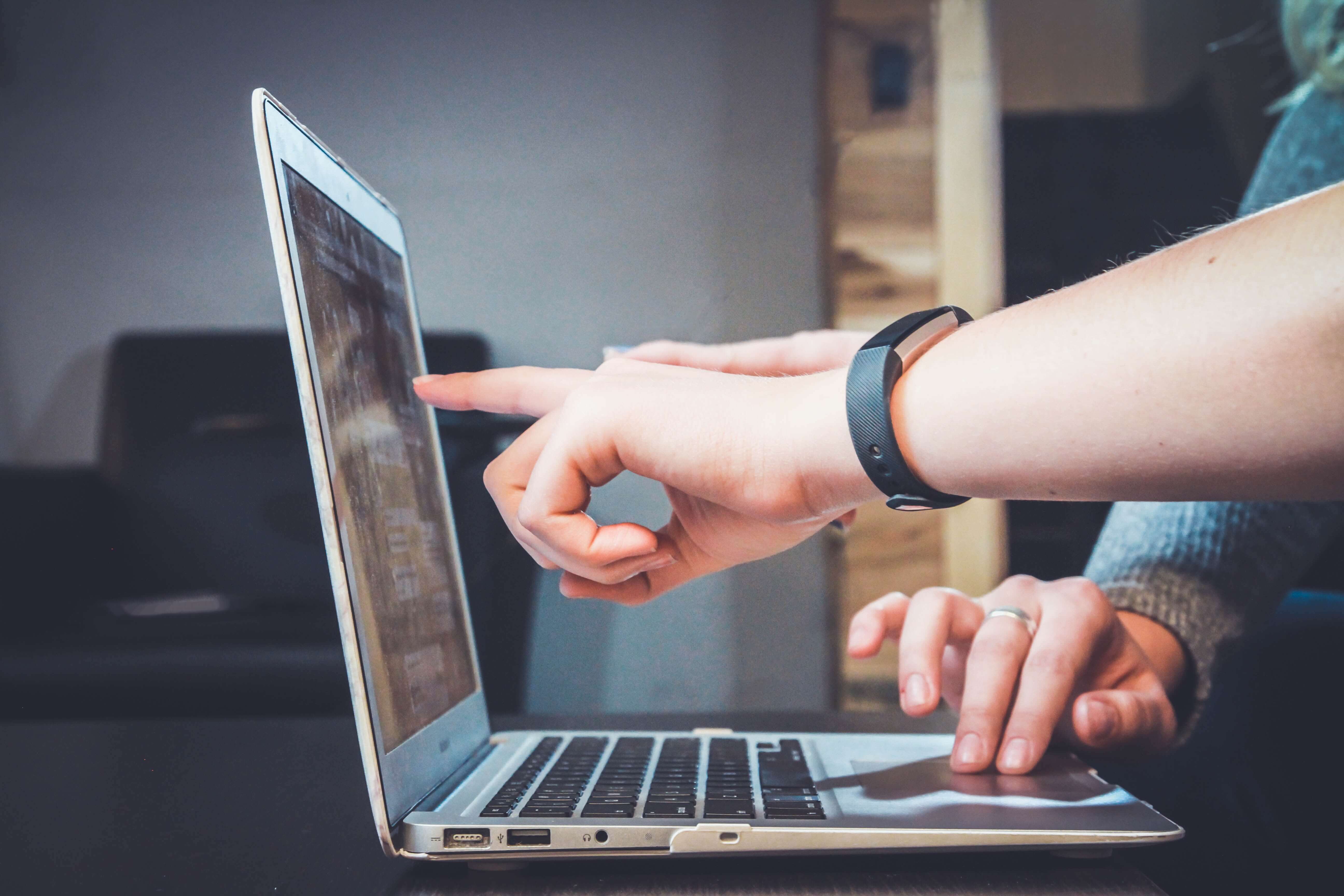 a man pointing on a laptop screen