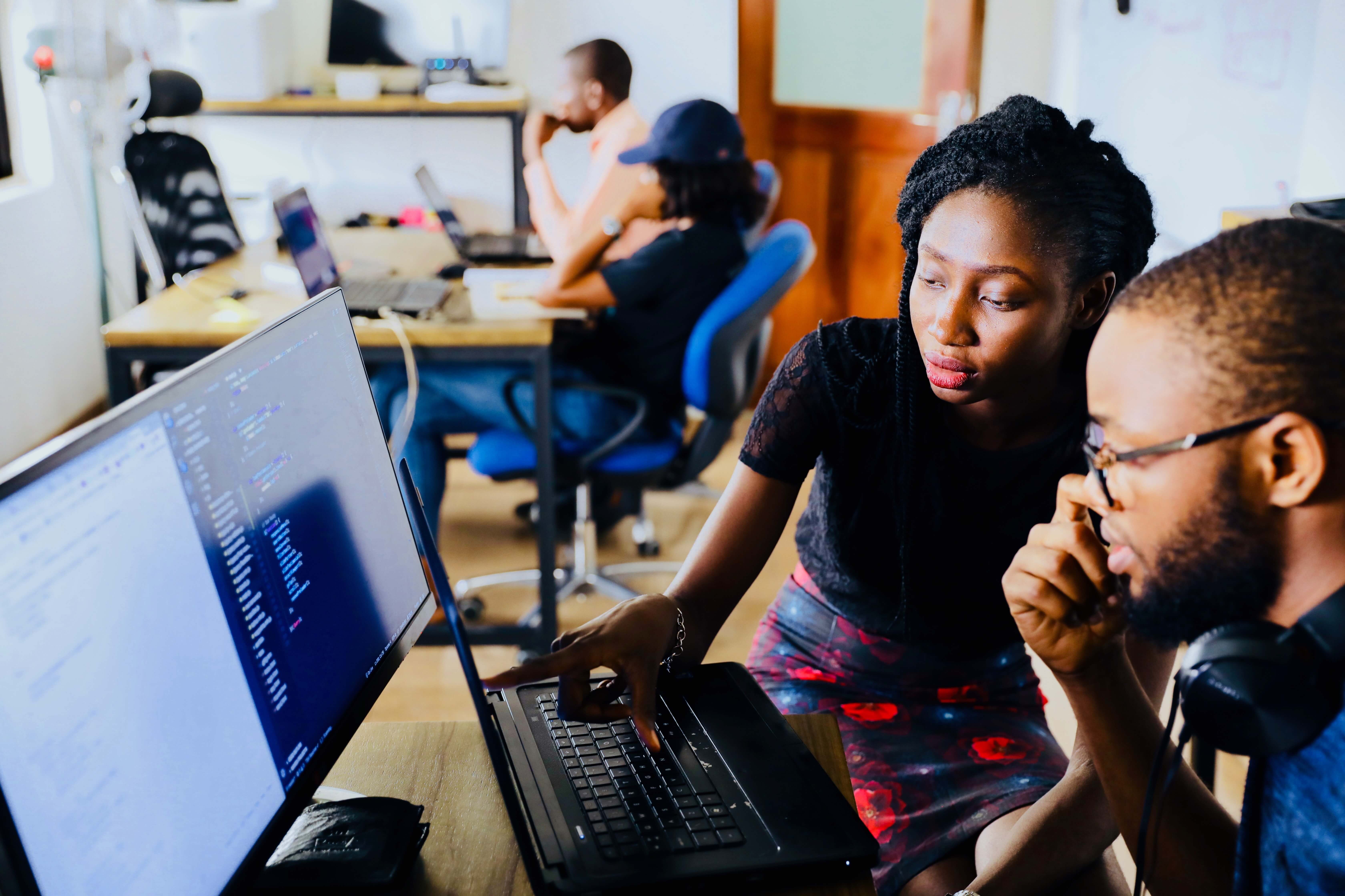 a man and a woman talking to each other and pointing their fingers the nearby desktop displaying CI/CD approach