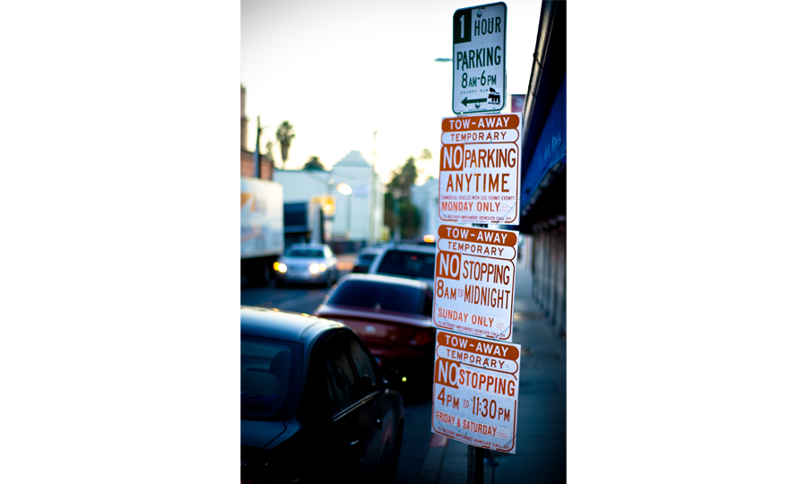 4 white and red parking signs placed on a pole in succession