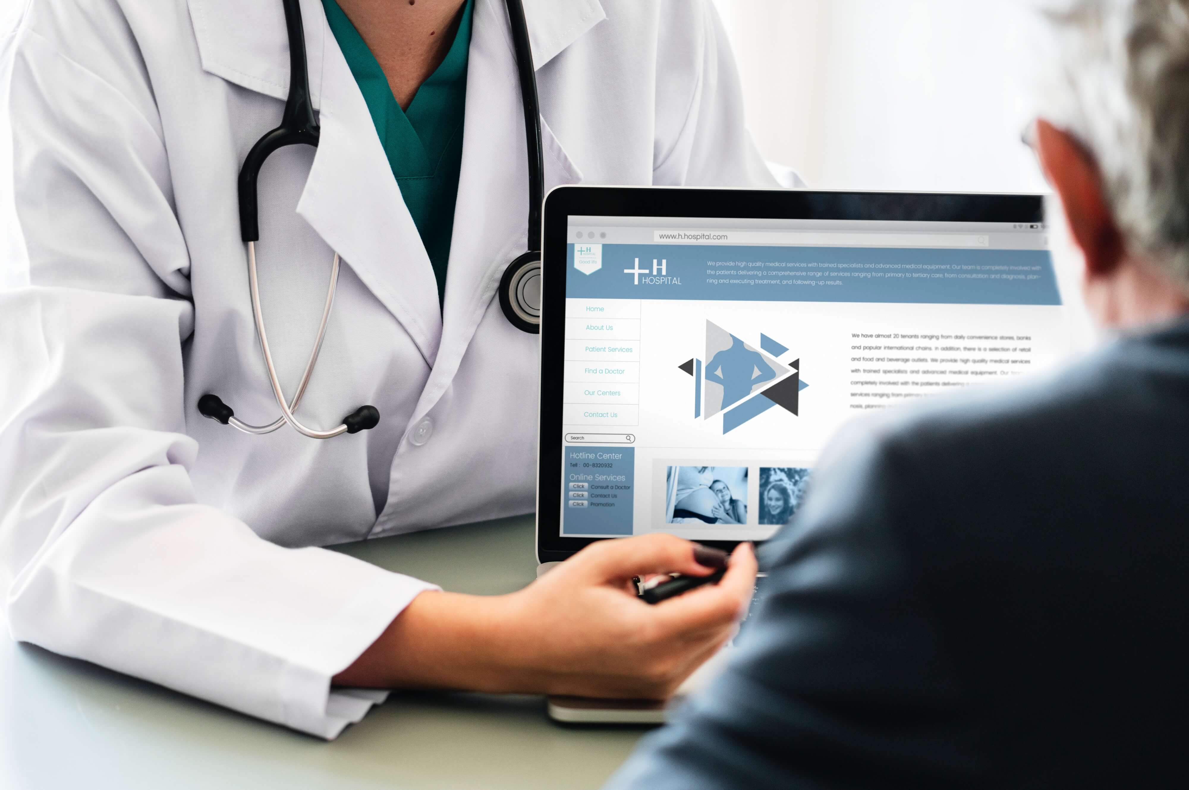 A doctor pointing his finger on his laptop screen as another man looks at it.