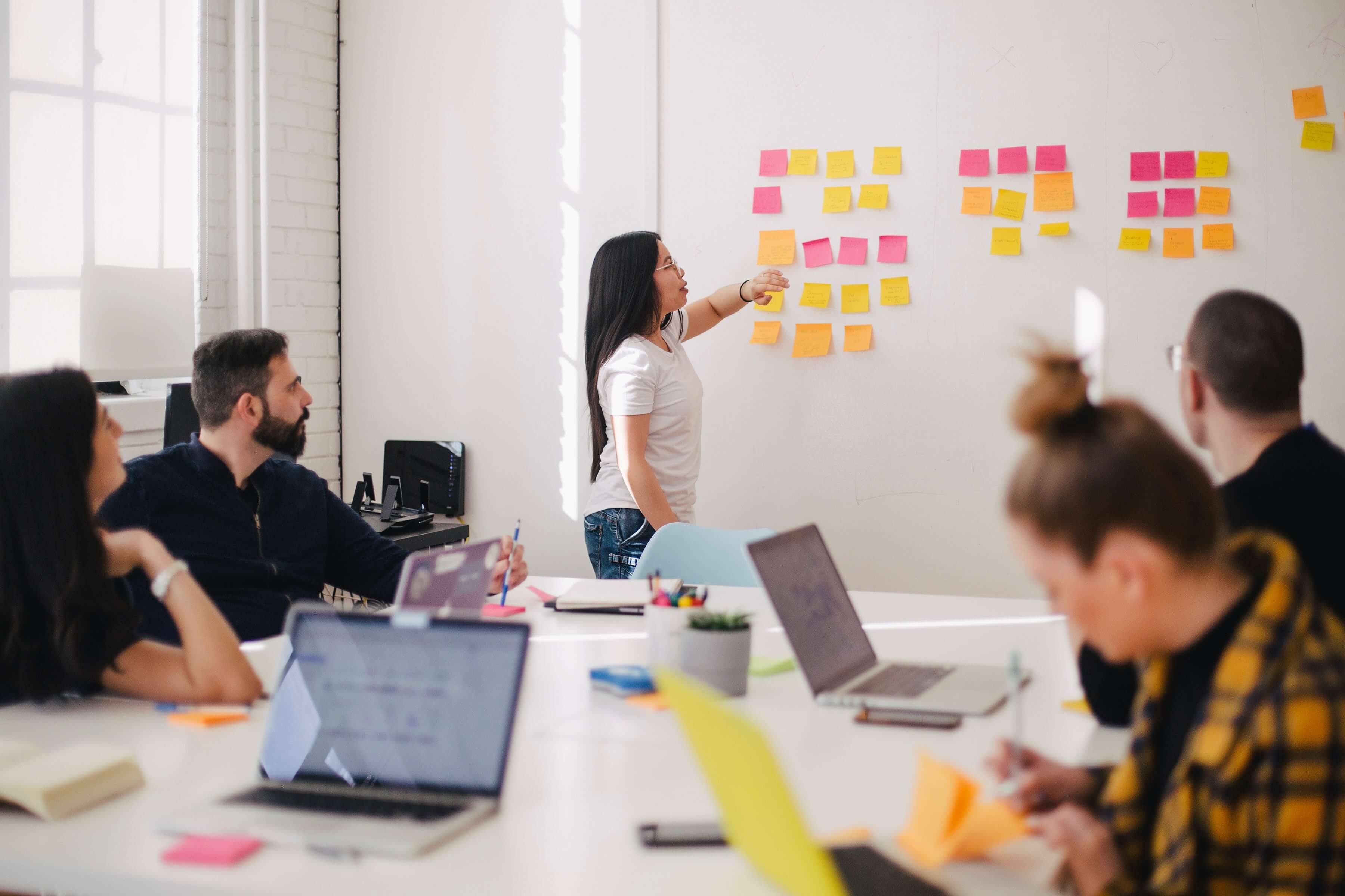 woman placing sticky notes on wall in a meeting