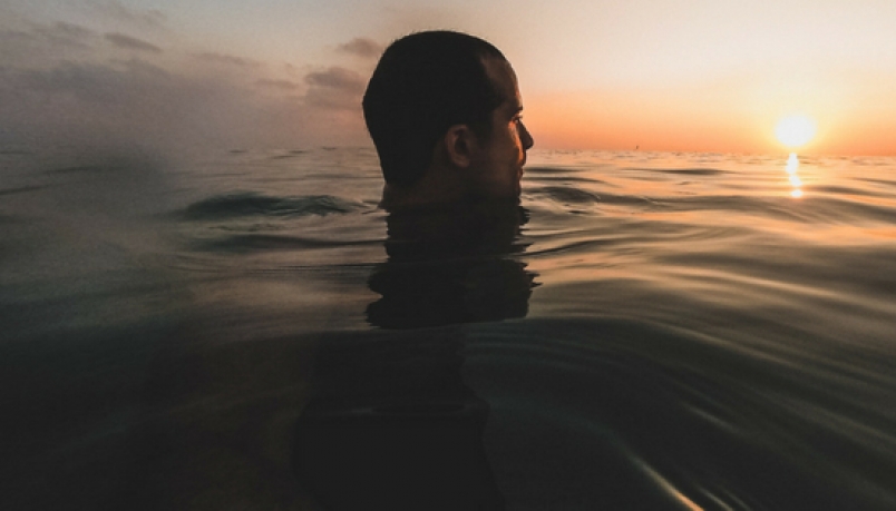 blog banner with a man swimming as the sun rises