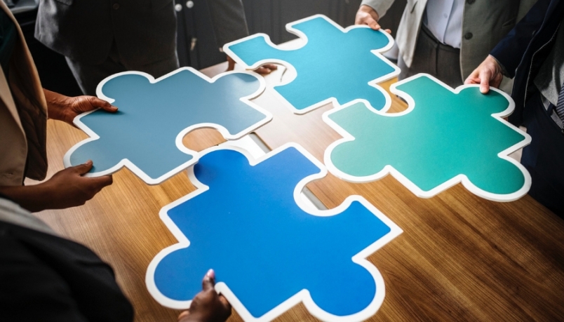 four blue piece of jigsaw puzzle held by four hands