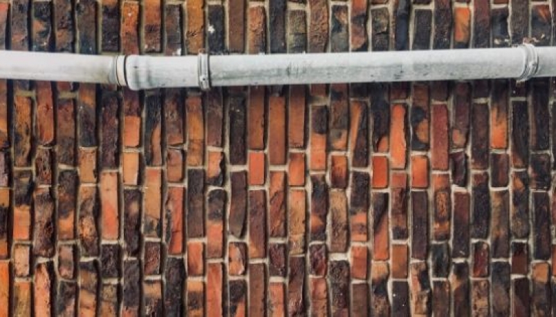 a pipe against a bricked wall