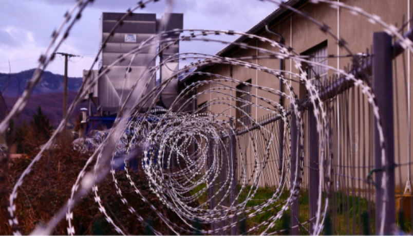 illustration image showing stainless steel spiral coiled bulb wire with a brown building in the background covered with green grass and cloudy sky above