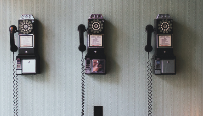 Three vintage telephones on a wall.