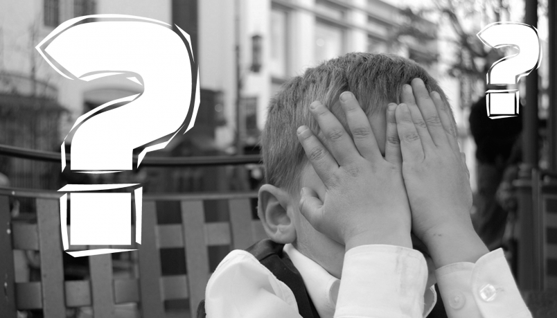A child has his face covered with his hands and two question marks are on both his sites. 
