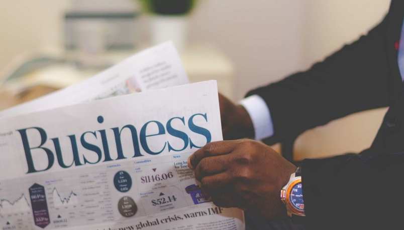 A business newspaper can be seen in the hands of a man.