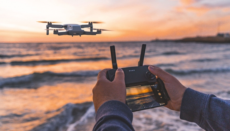 Someone is seen flying a drone on a beach over the ocean.