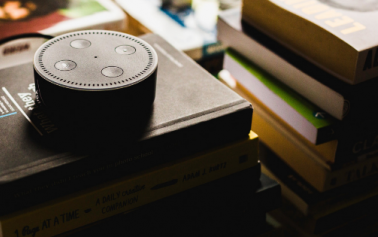 Amazon echo dot, a conversational UI based device, kept on a pile of books