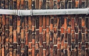 a pipe against a bricked wall