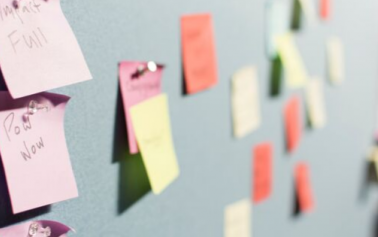 Sticky notes of different colours pasted on a wall to explain content strategy and ux writing
