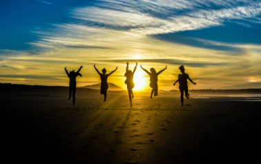 a group of people jumping in the air with sun rising in the background