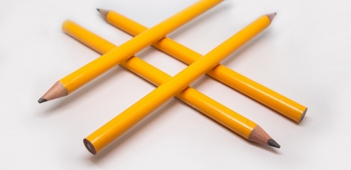 Image of four yellow pencils placed in a hashtag symbol on white background 