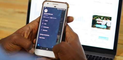 Image of hand holding a phone and a laptop is placed as a background