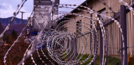 illustration image showing stainless steel spiral coiled bulb wire with a brown building in the background covered with green grass and cloudy sky above