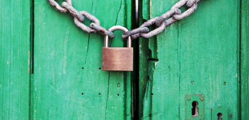 metal lock hanging on a green wooden door