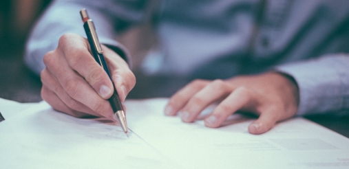 A man is seen signing a bunch of papers.