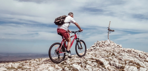A person is riding a bike over a mountain top.
