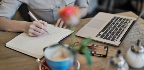 A woman is seen making notes from her laptop.
