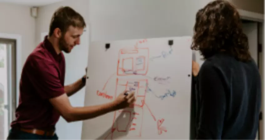 a man is explaining on the board while a woman is listening